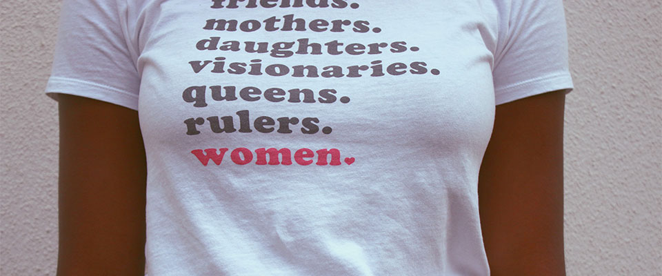 Woman wearing a T-shirt stating: Mothers, Daughters, Visionaries, Queens, Rulers, Women.